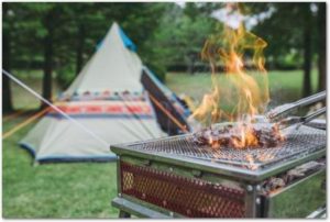 キャンプ場のテントの手前で肉を焼いている様子